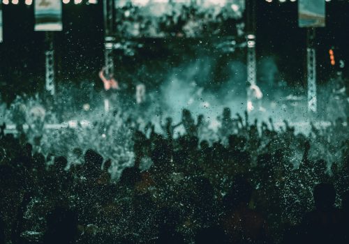 silhouettes of concert crowd in front of bright stage lights, pool party